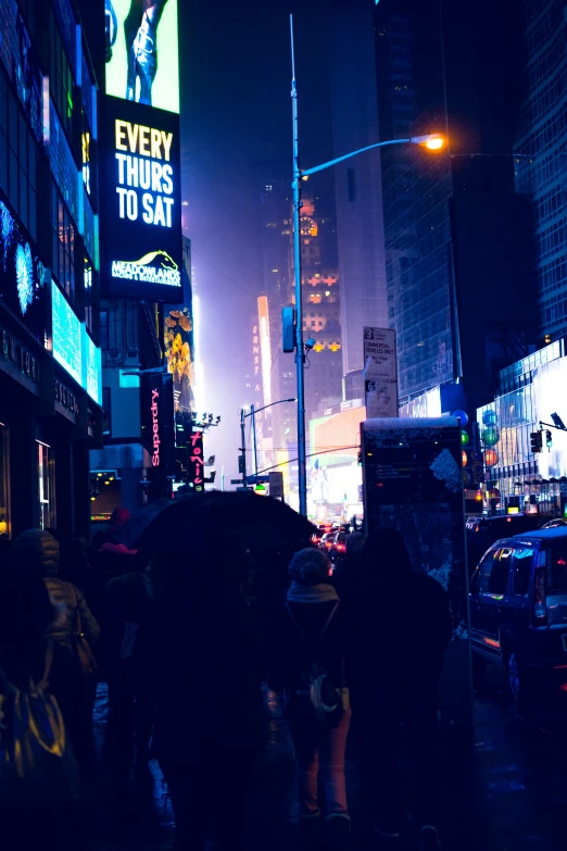 people are walking under the lights of a city street