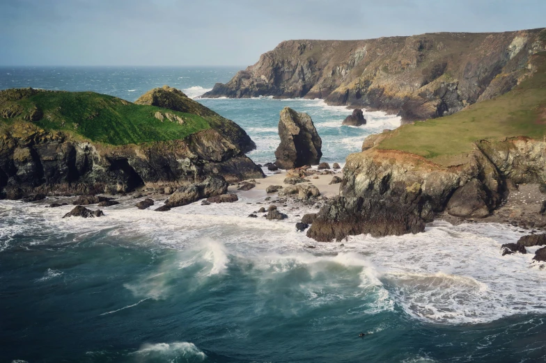 water splashes into the ocean and near rocks that are on the shore