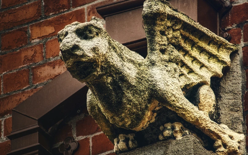 an ornate sculpture made out of cement stands against a brick wall