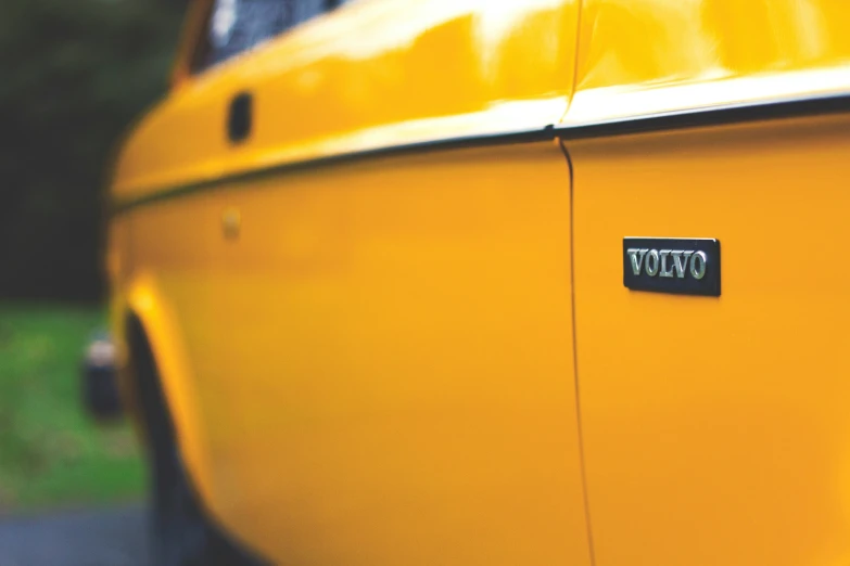 the trunk of an old yellow car with a black top