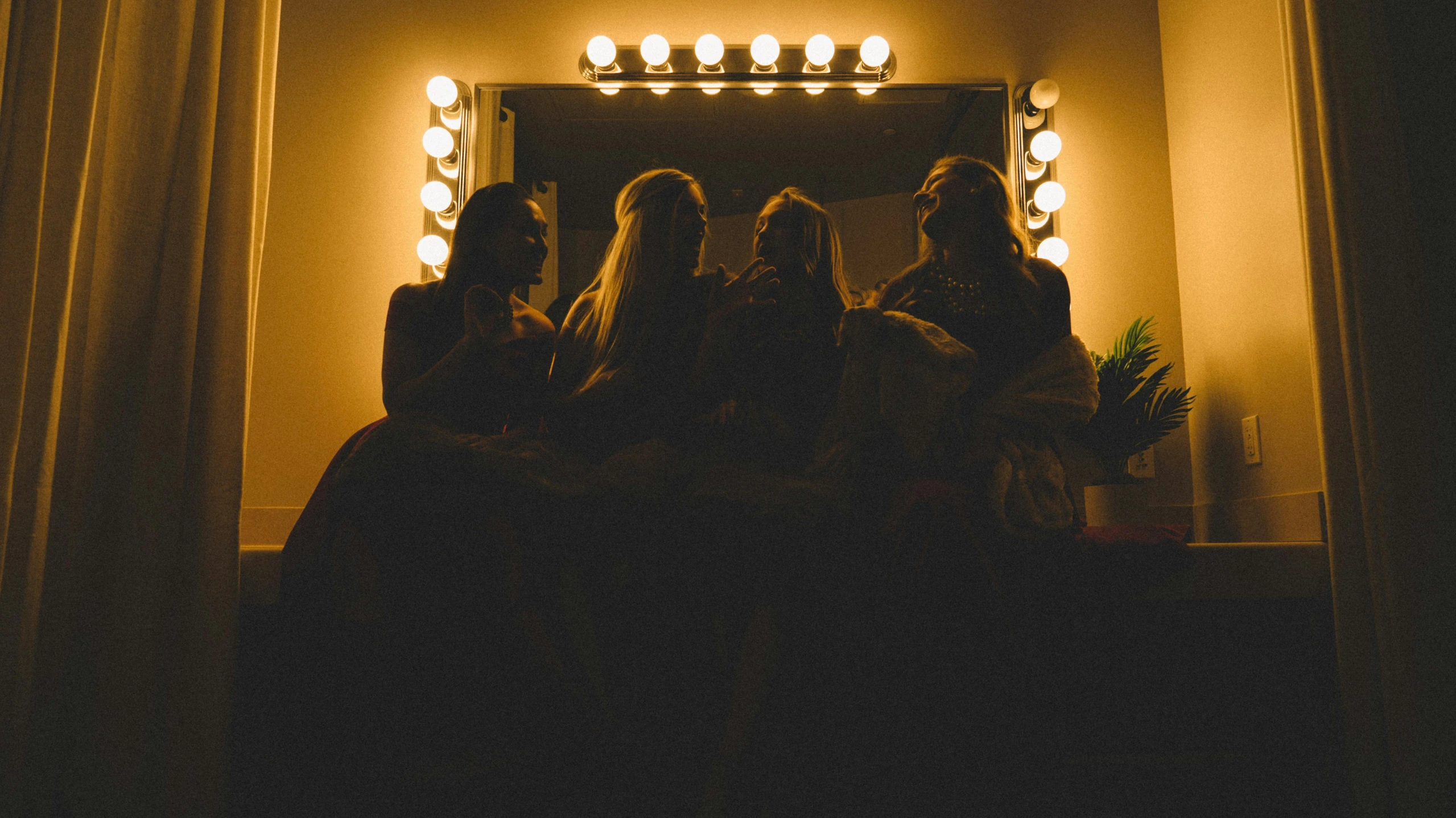 the group of friends are sitting around the bathroom sink