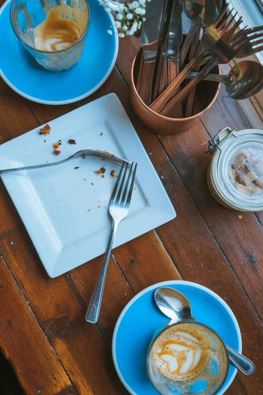 an empty plate with a fork and a cup of coffee