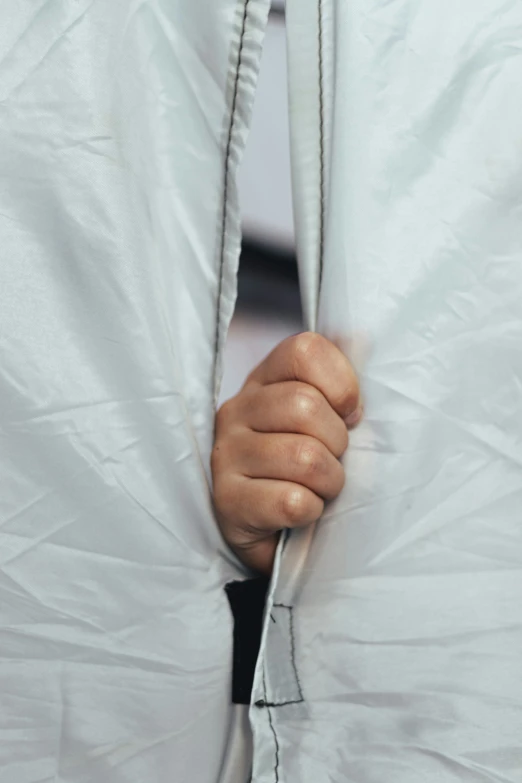 a close - up of a person pulling the zipper of a white coat