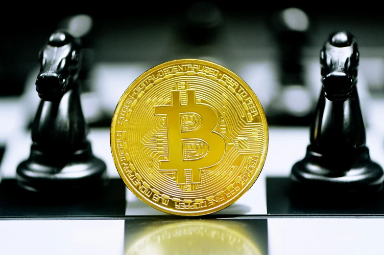 a golden bitcoin sits on top of a chess piece