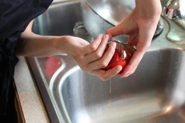 a person is washing food in the kitchen sink