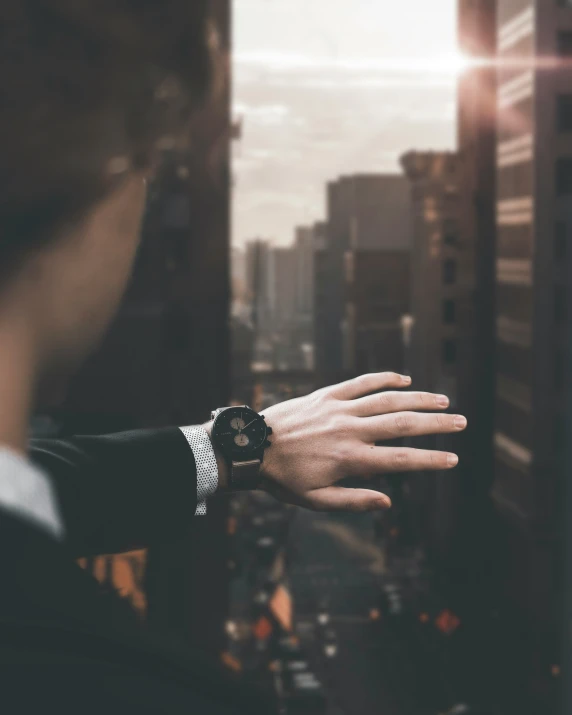 a hand reaching for soing off the edge of a window with city view in background