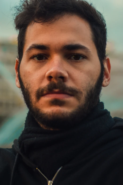 a young man wearing black and wearing a cross - neck hoodie