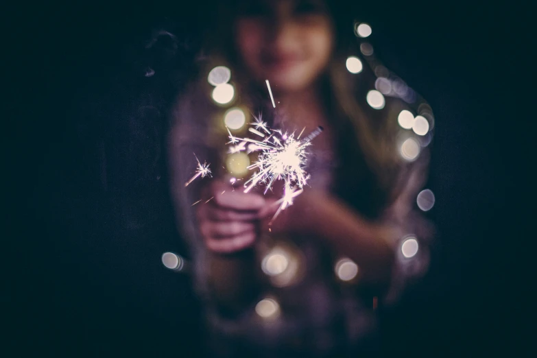 a woman holding onto a lite up sparkler