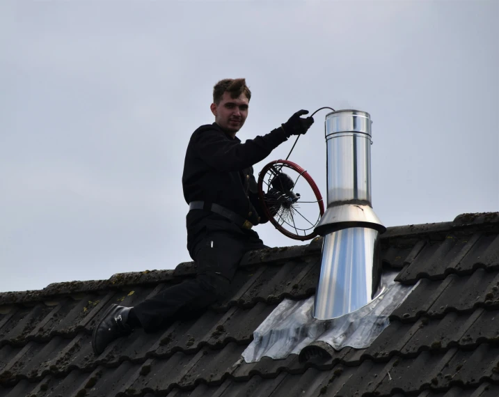a man on top of the roof fixing a bicycle wheel