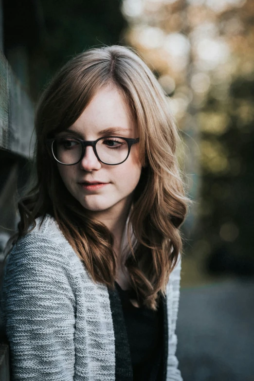 a woman with glasses standing in front of a building