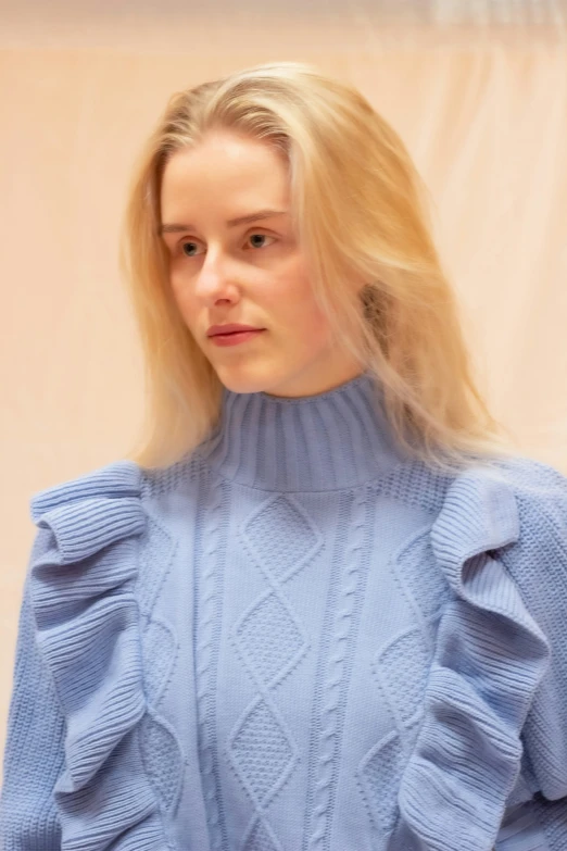 a woman with blonde hair is wearing blue sweater and jeans