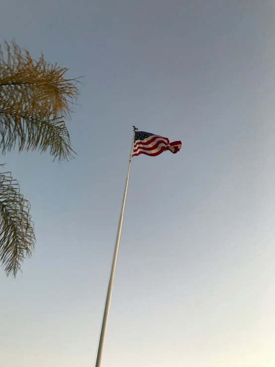 the american flag waving in the breeze, atop a pole