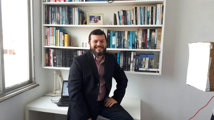 a man in a suit poses for a po in his office