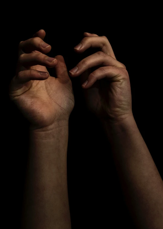 a dark image of two hands reaching to each other