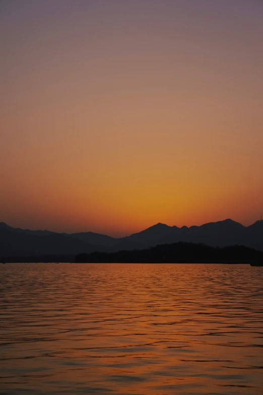 the sunset shines bright behind mountains in the ocean