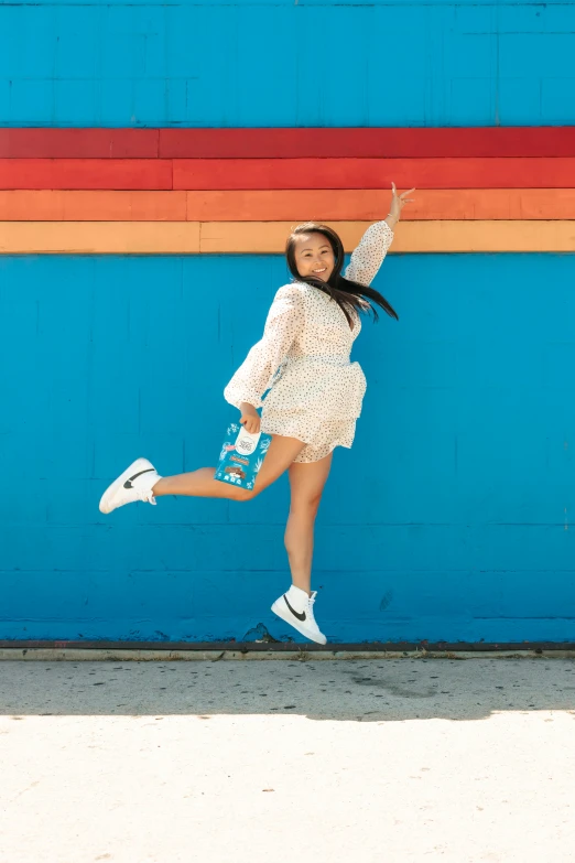 a girl jumping up against a wall on the sidewalk