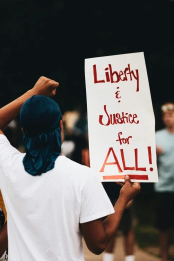 a man holding a sign that says liberty and justice for all