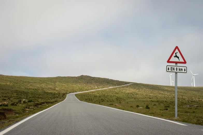 an empty road with a very steep hill behind it