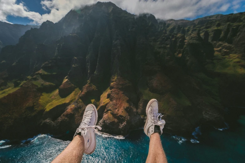 a pair of feet sitting in the water with mountains