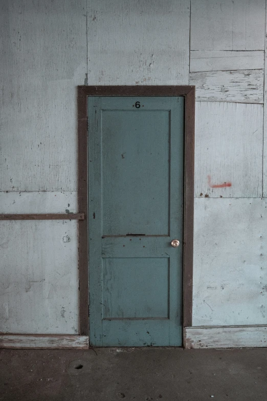 a closed blue door in the side of a white building