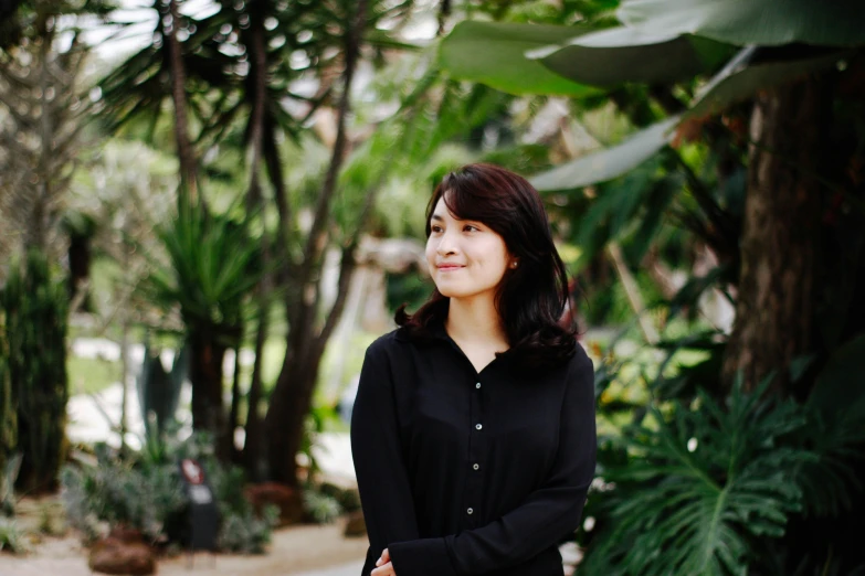 a beautiful asian woman standing next to palm trees