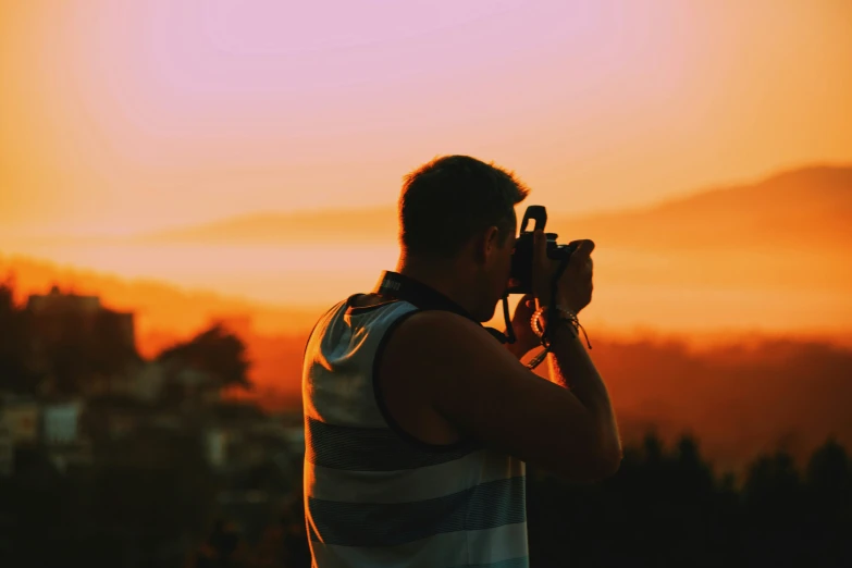 a man is taking a po of the sunset over a mountain