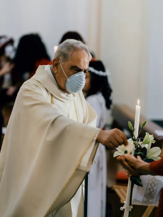 a man with a surgical mask and white gloves handing flowers to the person in front of him