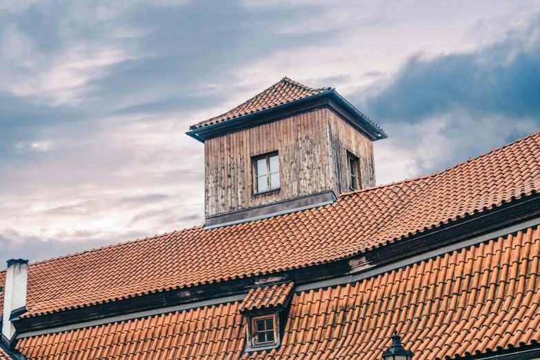 a red tiled roof that has a tall wooden tower