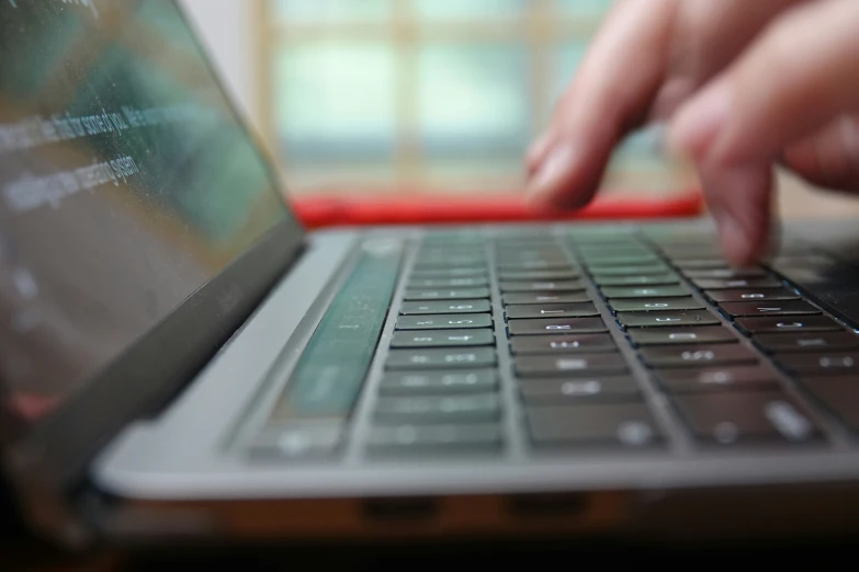 a hand is touching the keyboard of a laptop