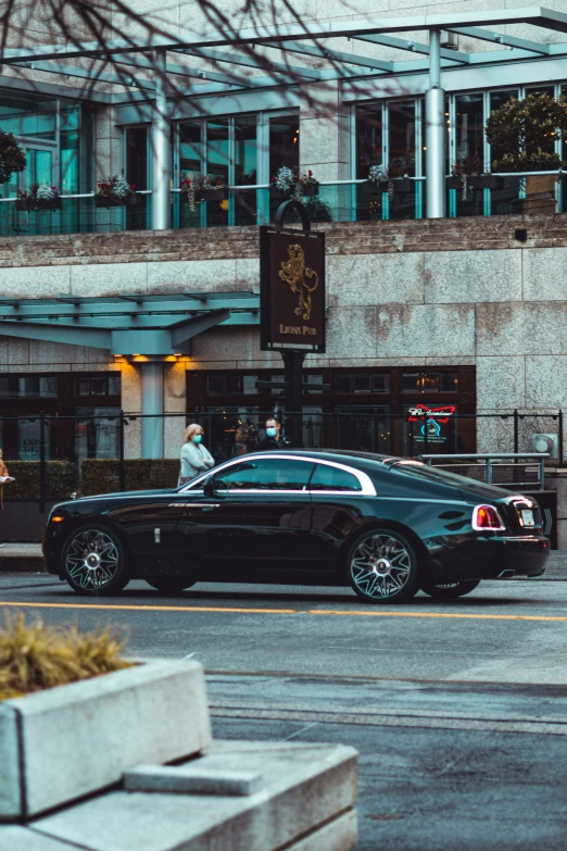 the luxury car drives past a building on a city street