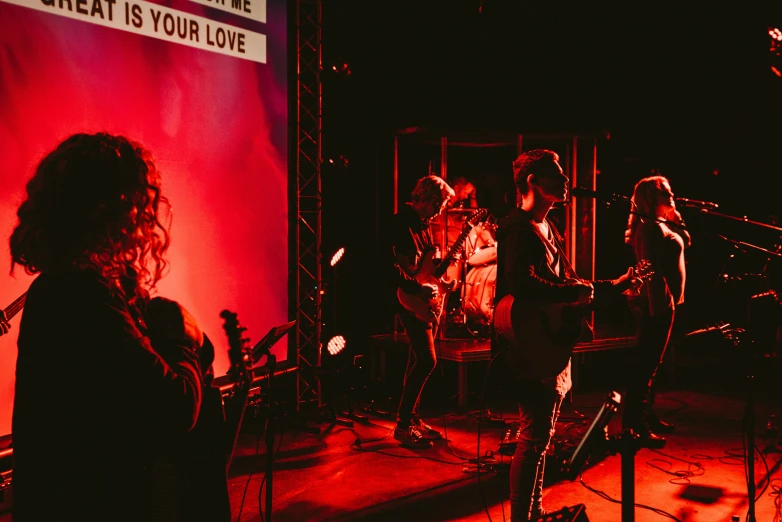 a band playing on stage at night with red light from behind