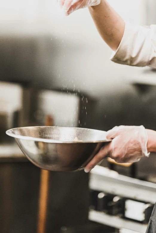 a chef holding up a bowl that contains liquid