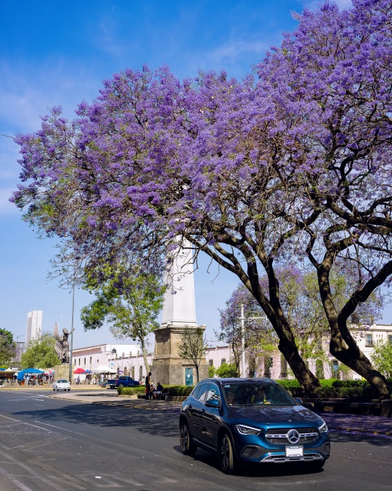 a blue car driving down a street next to tall buildings