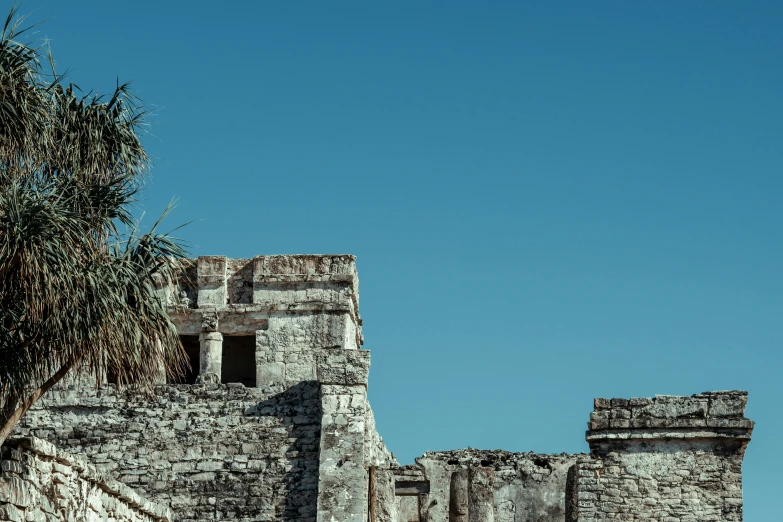 an old ruins structure is seen against a bright blue sky