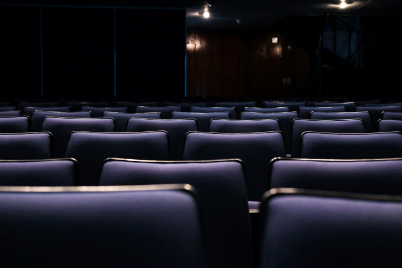 an empty auditorium with several rows of seats and one screen