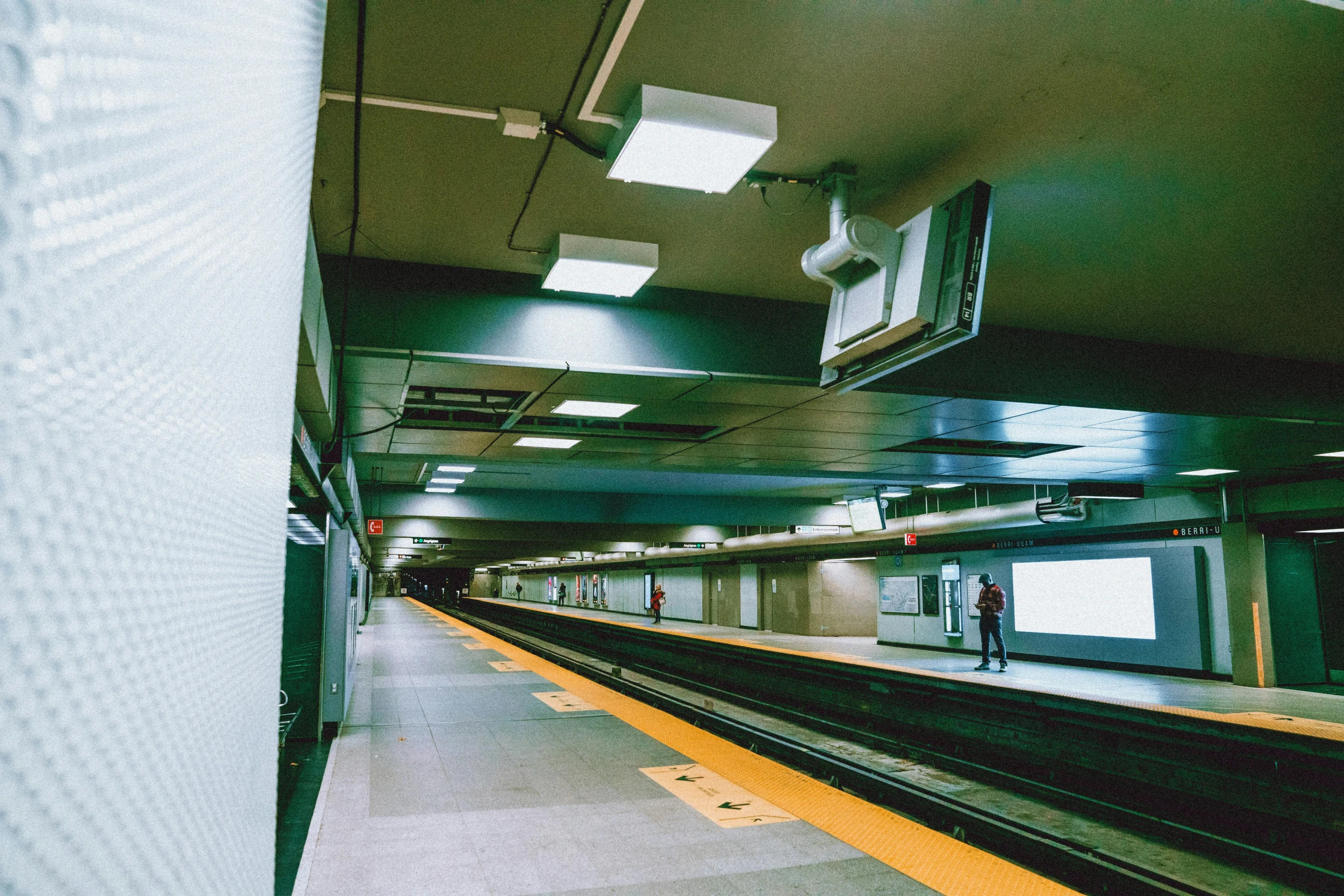 an empty train platform with people walking by