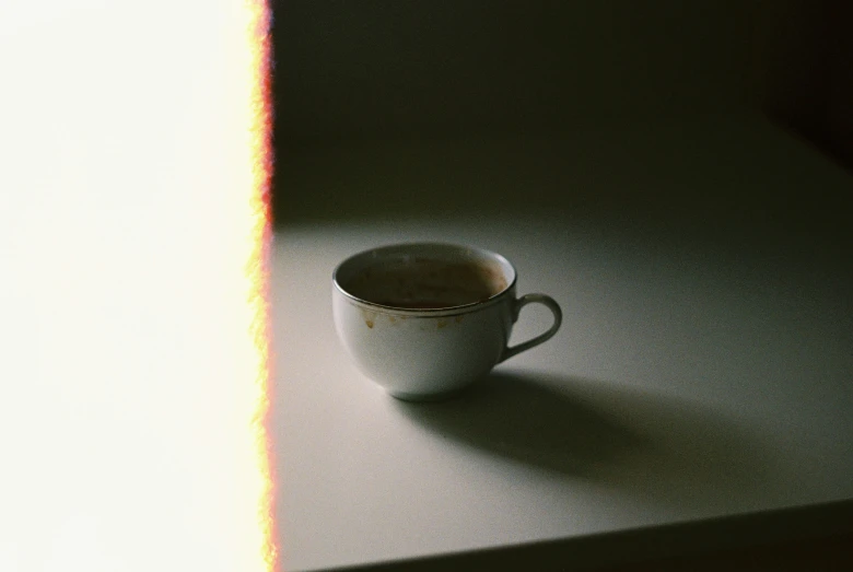 the shadow of a coffee cup is cast on a surface