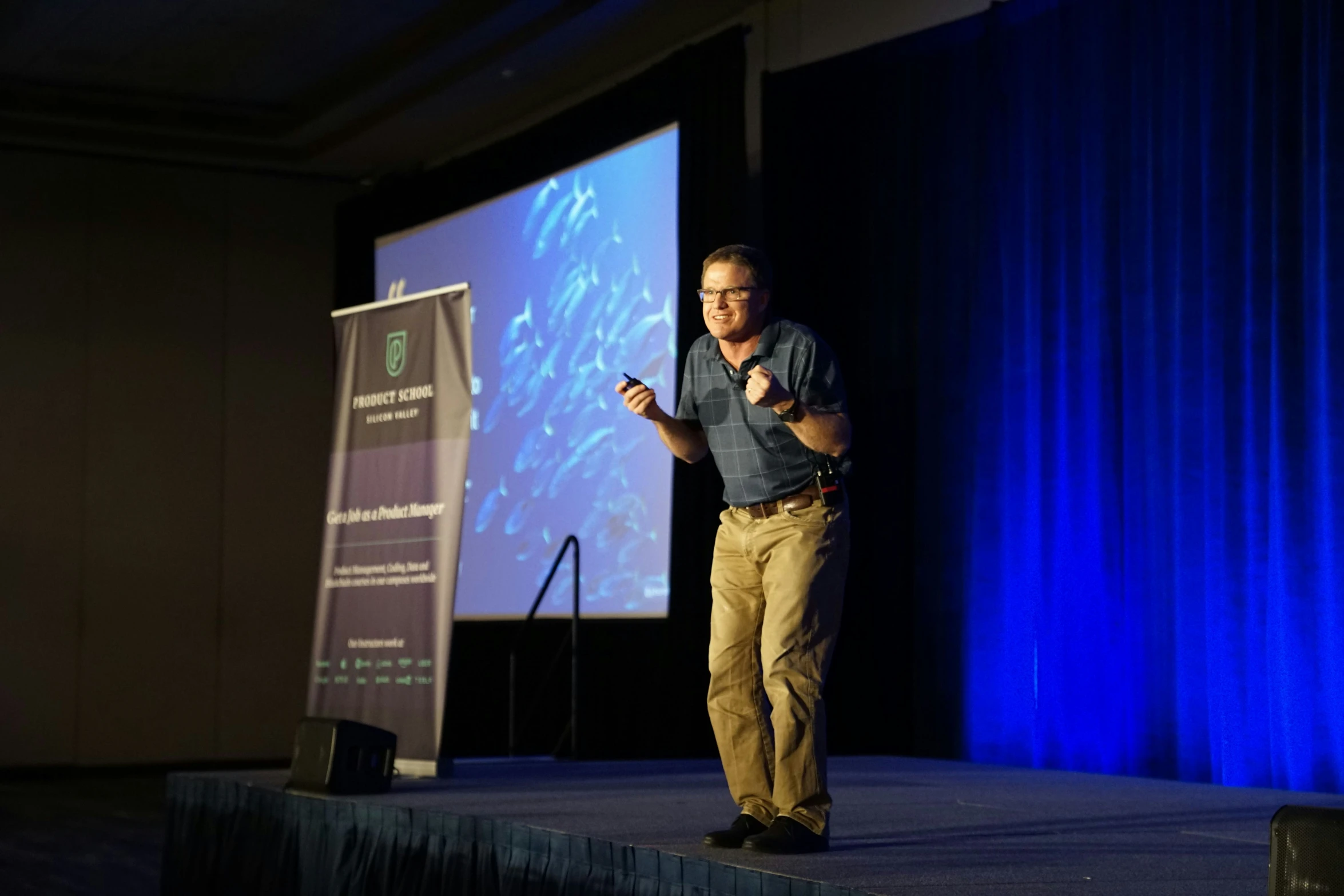 a man giving a presentation on stage with a microphone