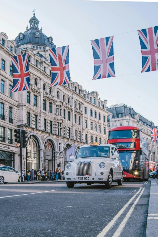 a london road with double decker buses and flags hanging above