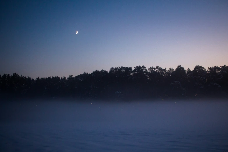 moon above an island in the ocean at dusk