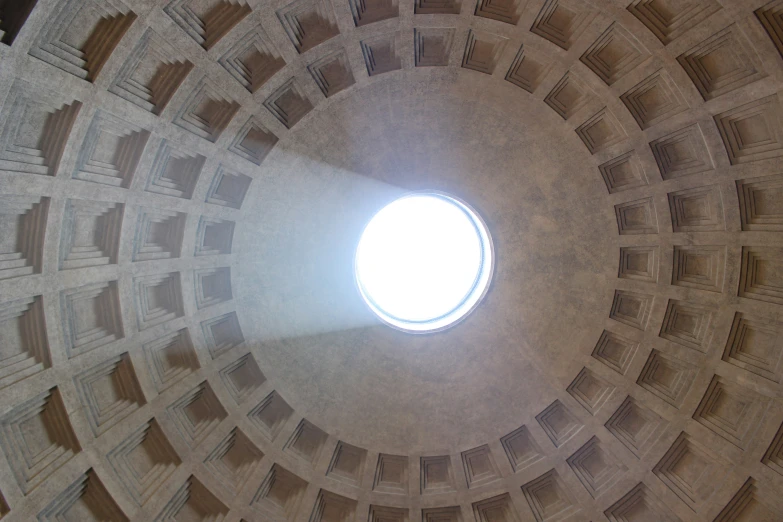 looking up at a small round sun light in the center of a building