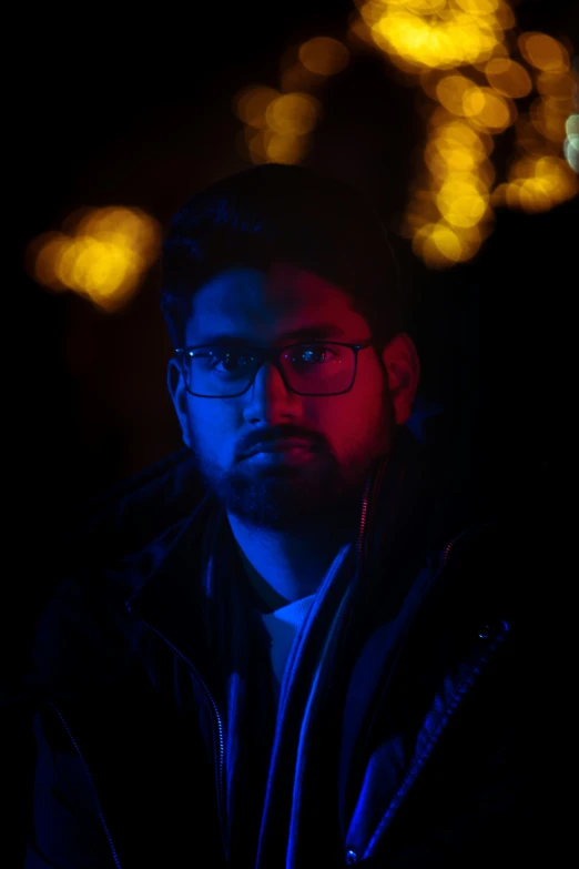 a man in glasses standing in the dark