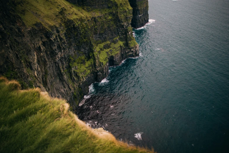 a cliff by the ocean with large cliffs in the water