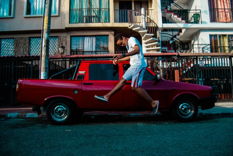 a young man running past a red truck and a spiral staircase