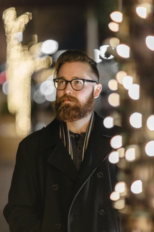 a bearded man in glasses is looking off into the distance