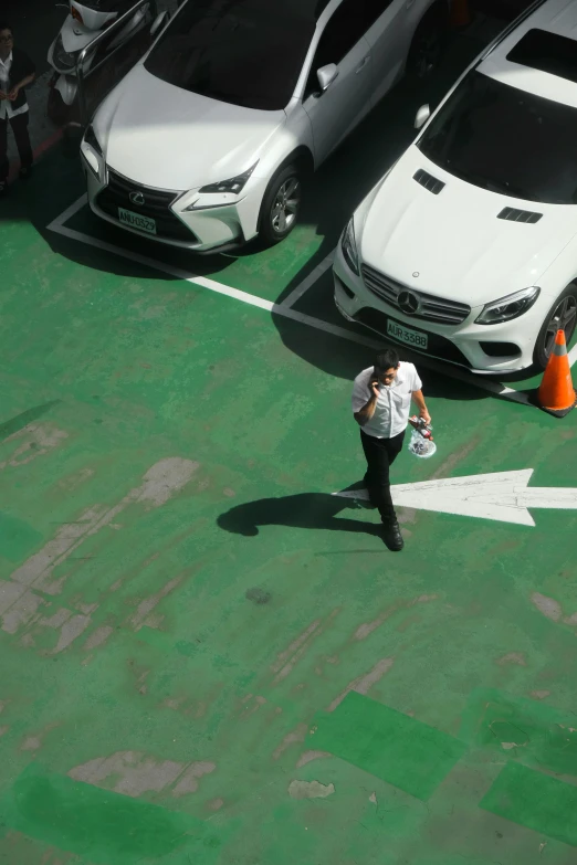 a woman walking down a parking lot past white cars