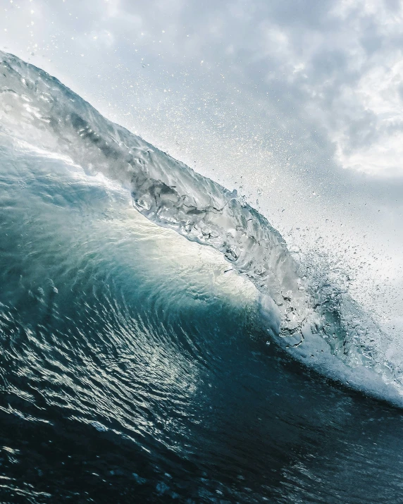 a wave rolling in to shore with grey clouds and white frothy water