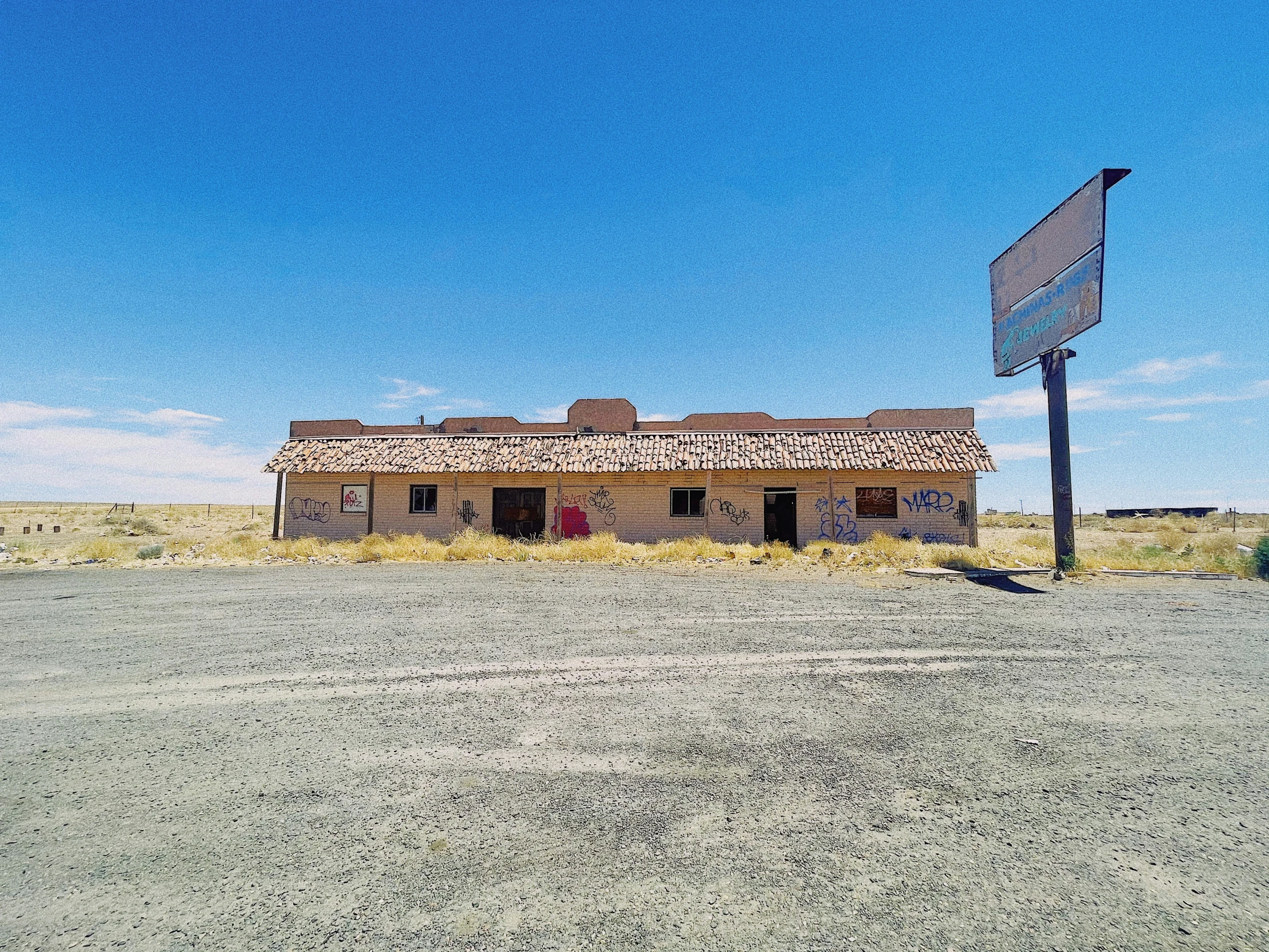 an abandoned house is next to a blue street sign