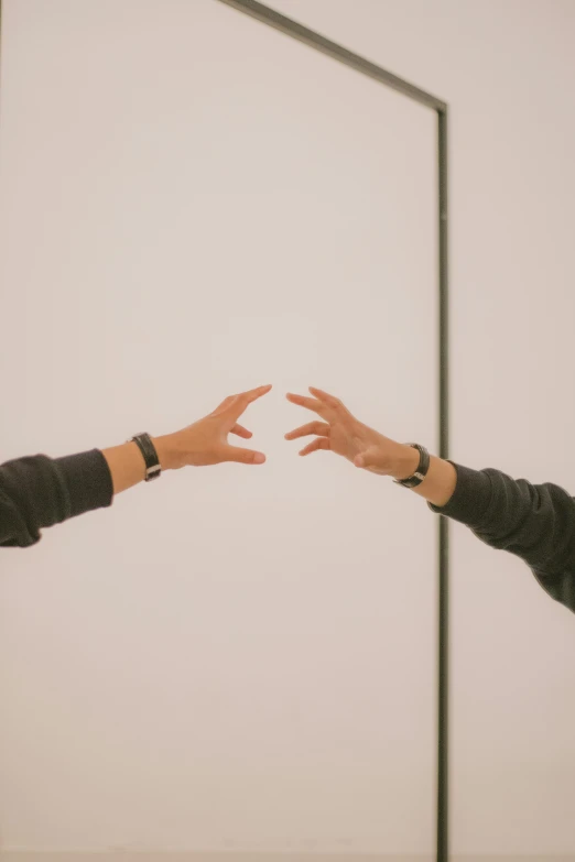 a man and woman holding their hands out in front of a white wall