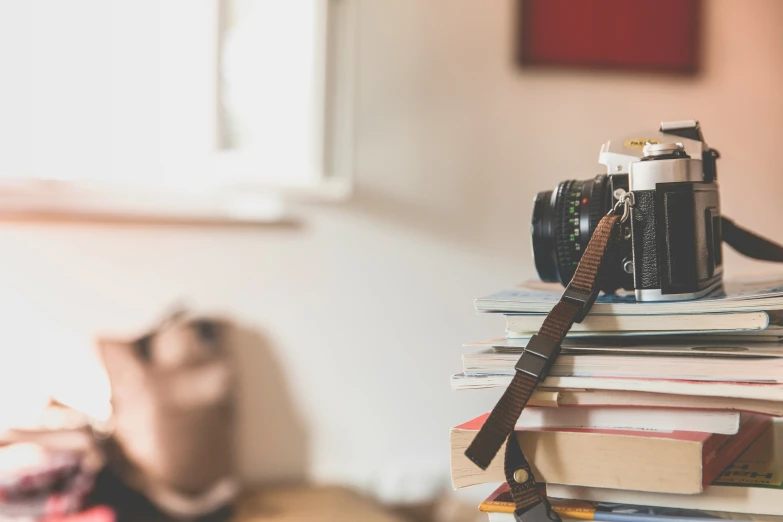 a pile of books on a bed and a camera